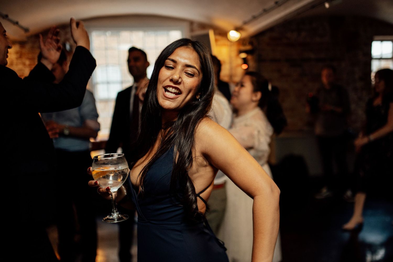 Guests dancing and celebrating at an evening wedding reception with warm lighting.
