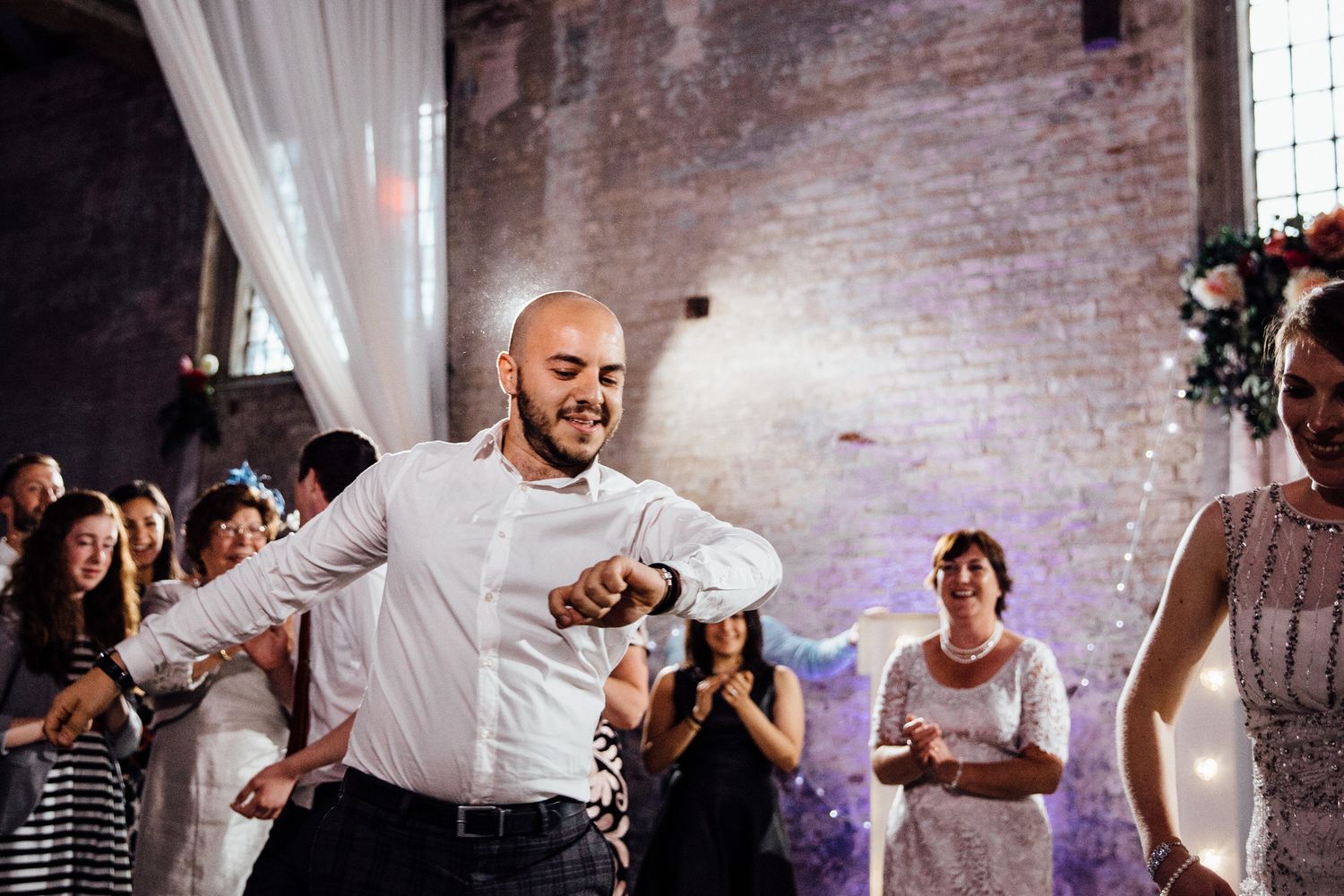 Wedding guests dancing and celebrating on the dance floor of an industrial-style venue.