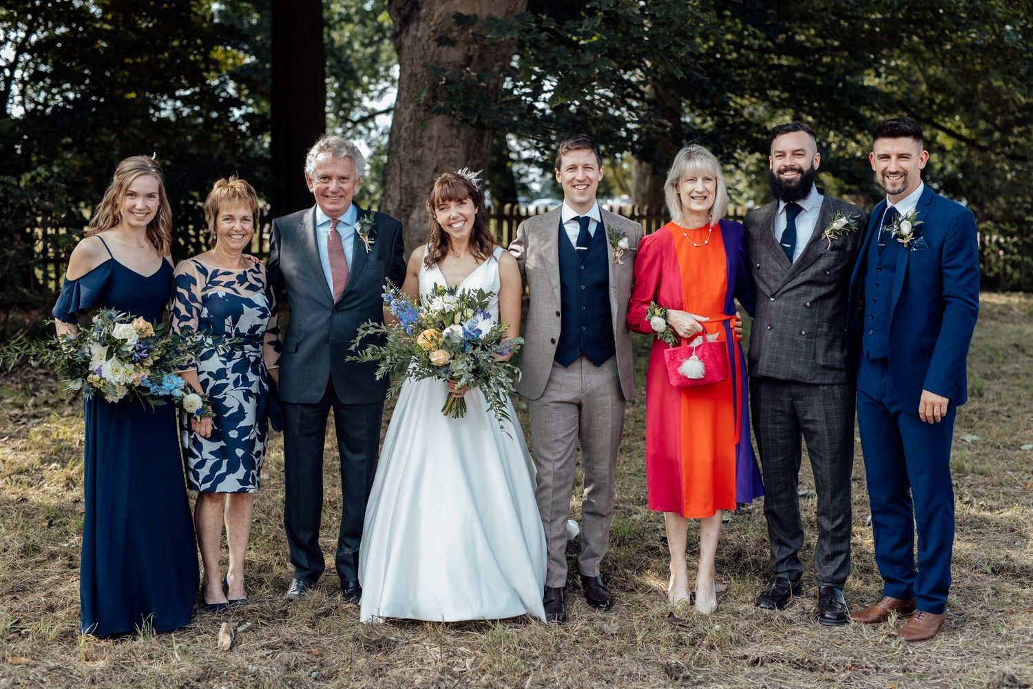 Formal wedding party photos with navy and floral attire against natural outdoor backdrop.
