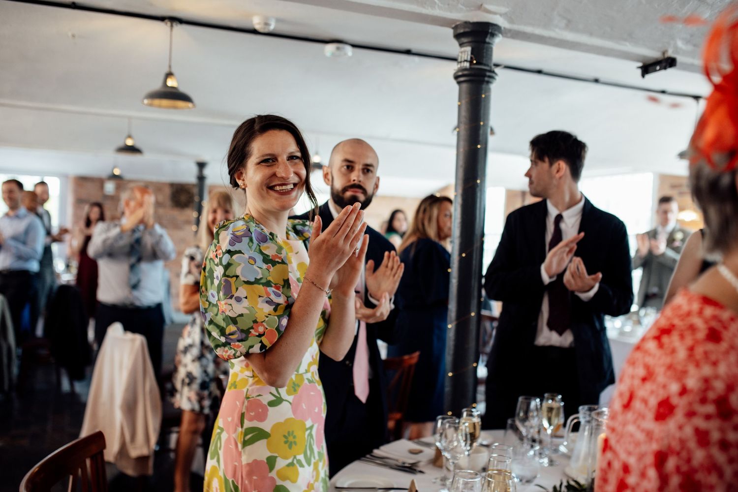 Wedding reception venue with guests applauding during celebration speeches.