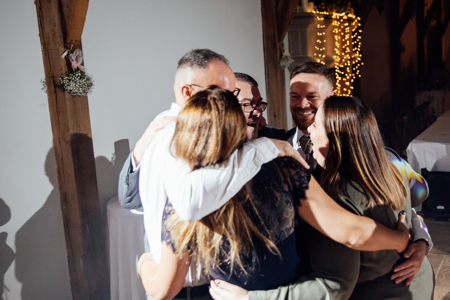 Wedding guests share joyful hugs and embraces during a celebration.