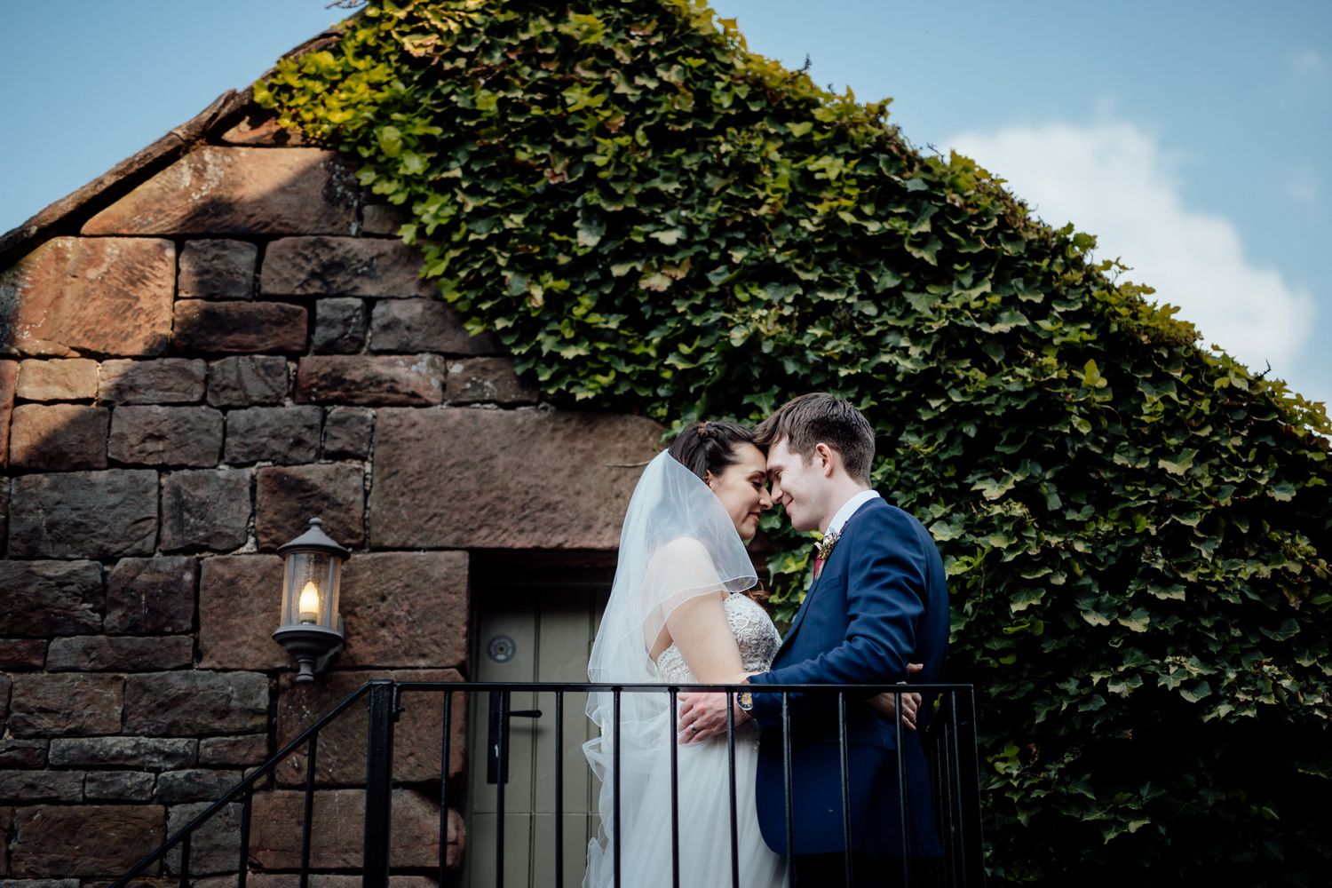 Stone building exterior with ivy covered walls and blue sky backdrop.