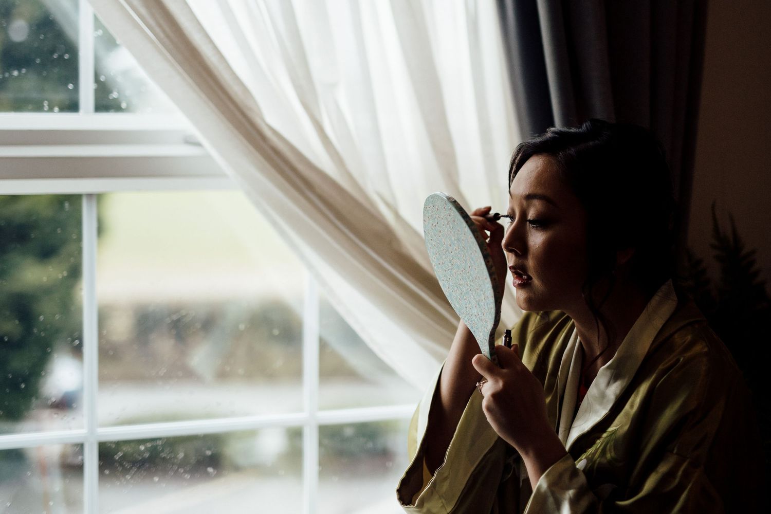 Soft window light illuminates a quiet moment during wedding preparations.