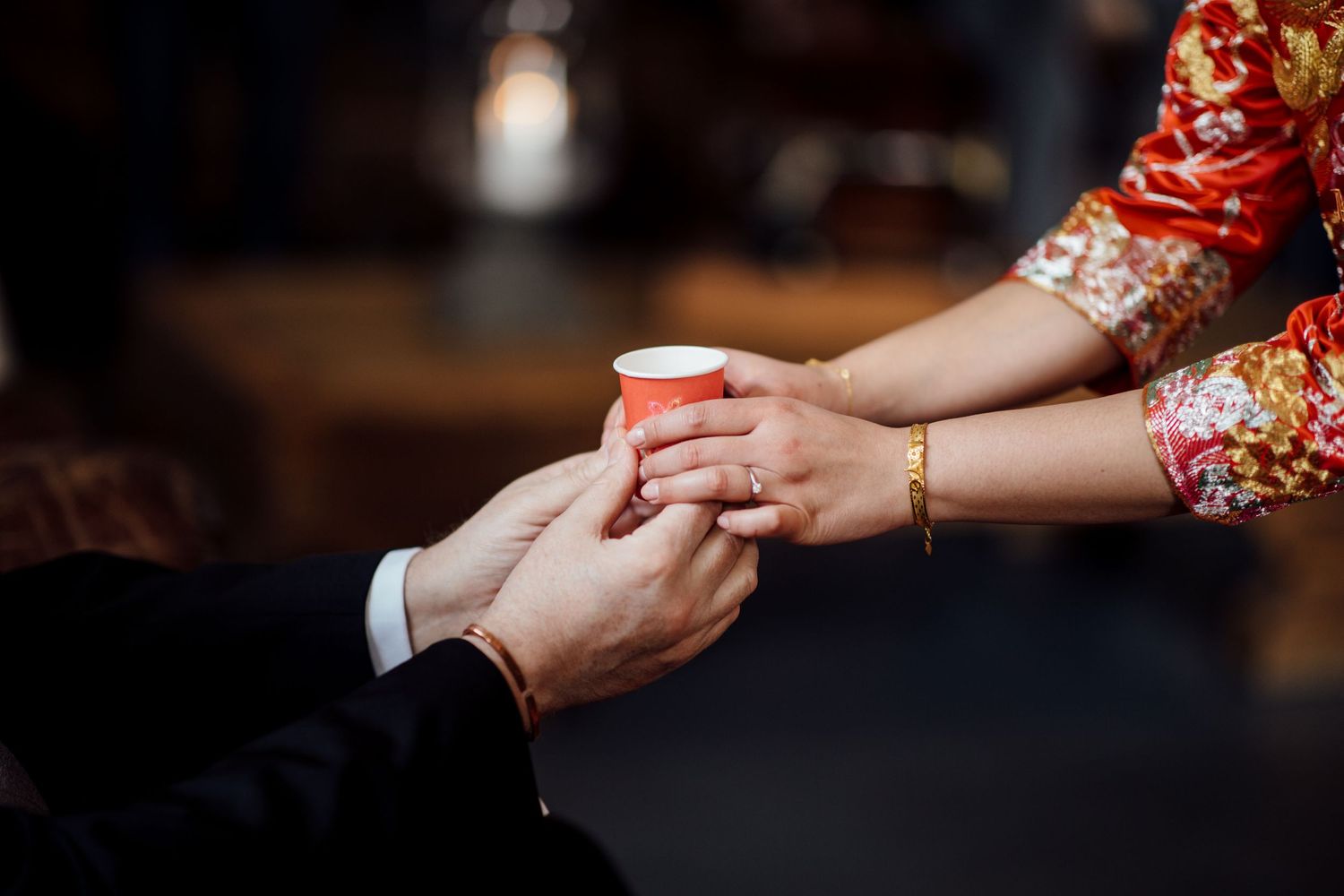 Close-up of hands exchanging tea cup during traditional Chinese tea ceremony.