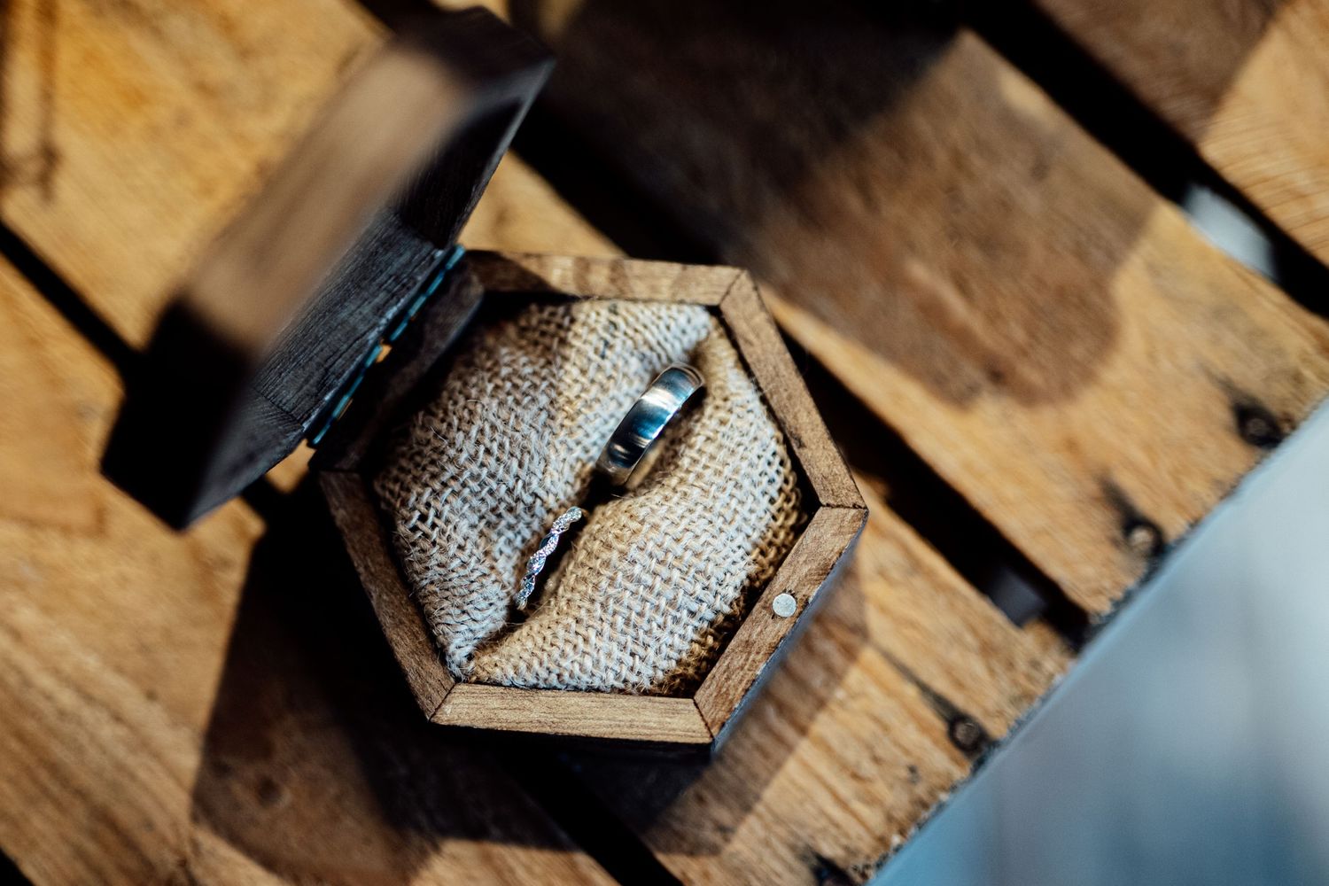 Close-up of wedding rings on rustic wooden surface with dramatic lighting.