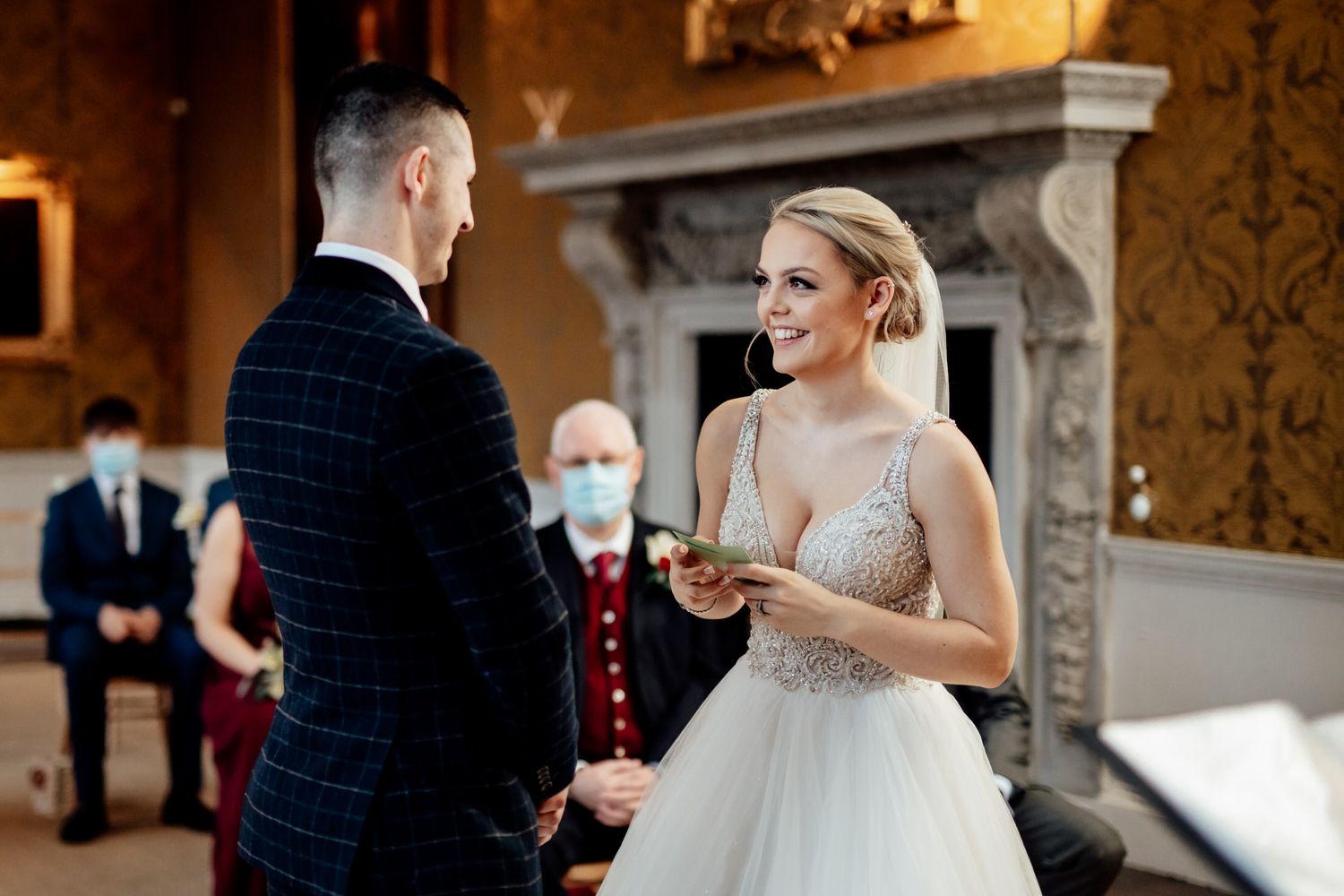 Couple dancing in an ornate ballroom with gold damask wallpaper and classical decor.