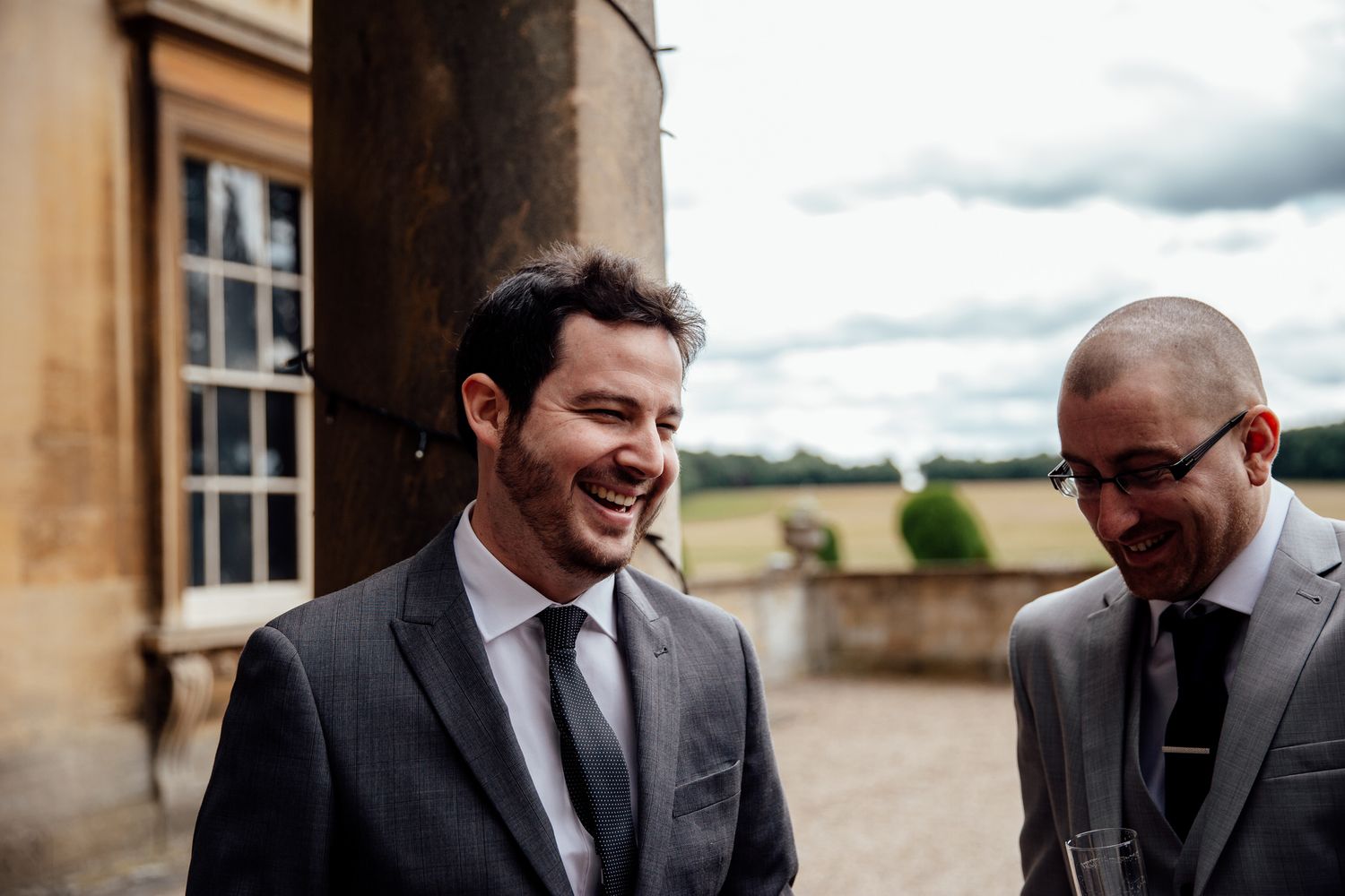 Candid moments of joy and laughter shared between wedding party members outside a stone building.