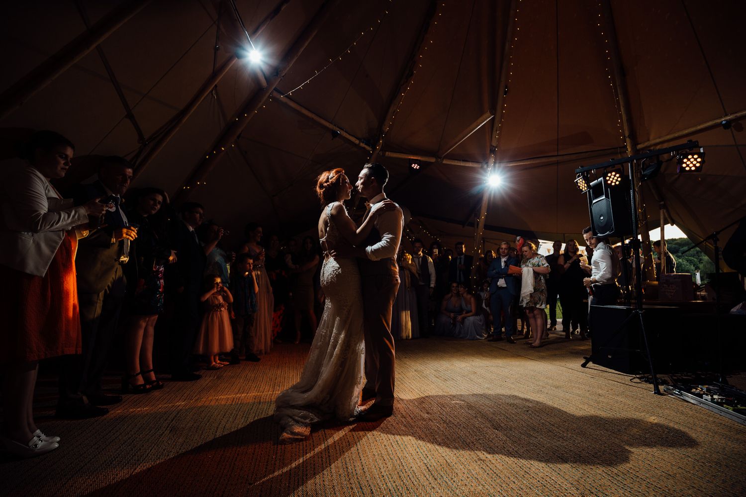 Atmospheric nighttime dance floor scene in a tipi with spotlights creating dramatic shadows.