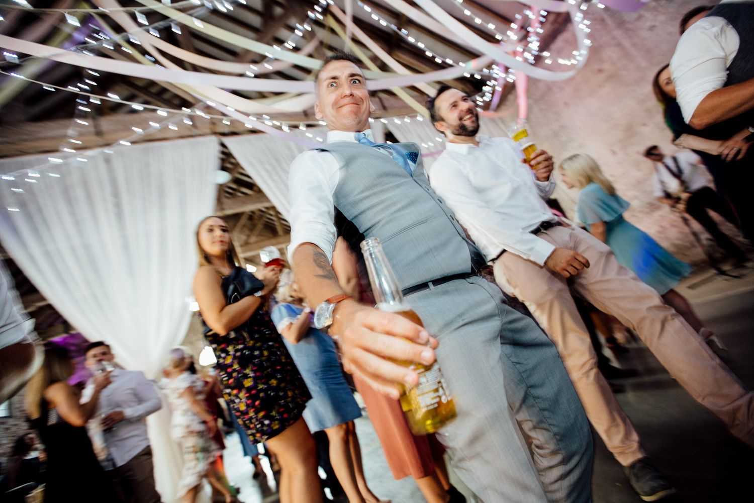 Wedding guests dancing and celebrating on a crowded dance floor at a reception party.
