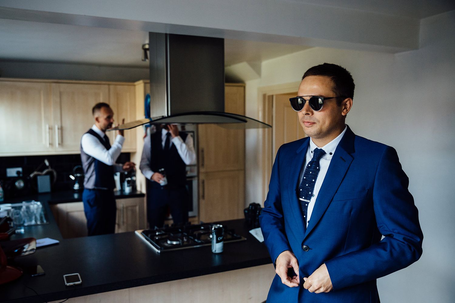 Groomsmen in navy blue suits getting ready in a modern hotel room.