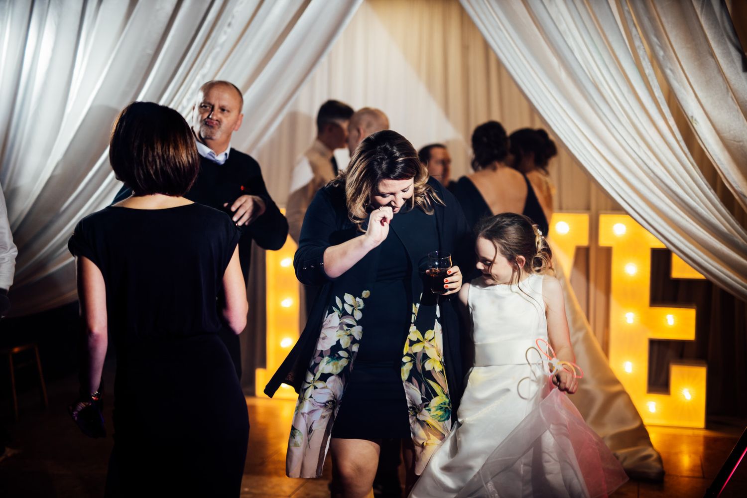 Wedding reception venue with elegant white draping and warm lighting.