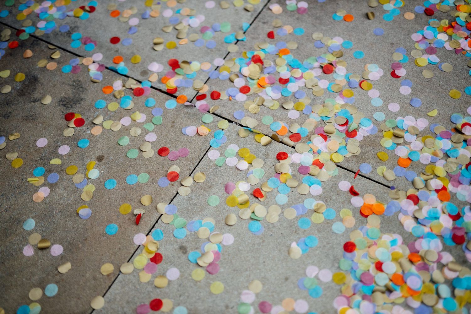 Colorful confetti scattered across concrete floor creating a festive pattern.