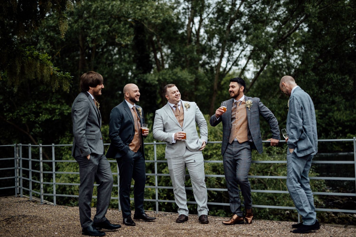 Wedding party members gather on a rustic bridge for outdoor photos.