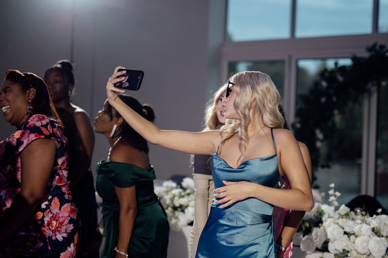 Wedding guests dancing and taking selfies during the reception celebration.