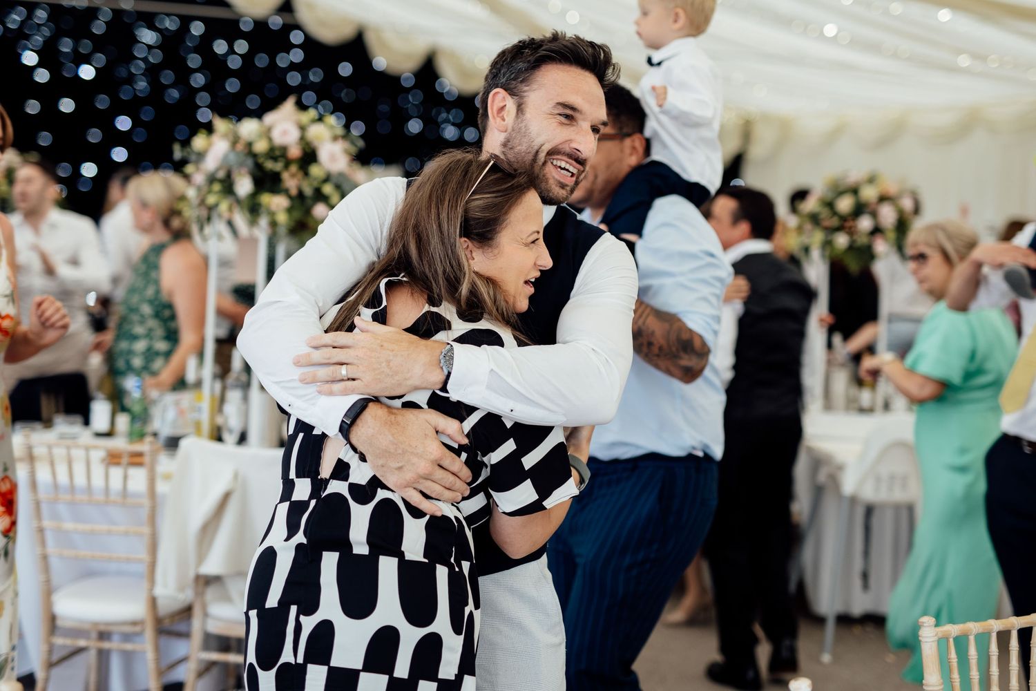 Wedding guests dancing and celebrating at indoor reception.