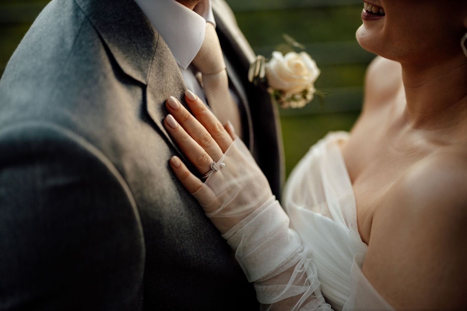 Close-up details of wedding couple embracing outdoors.