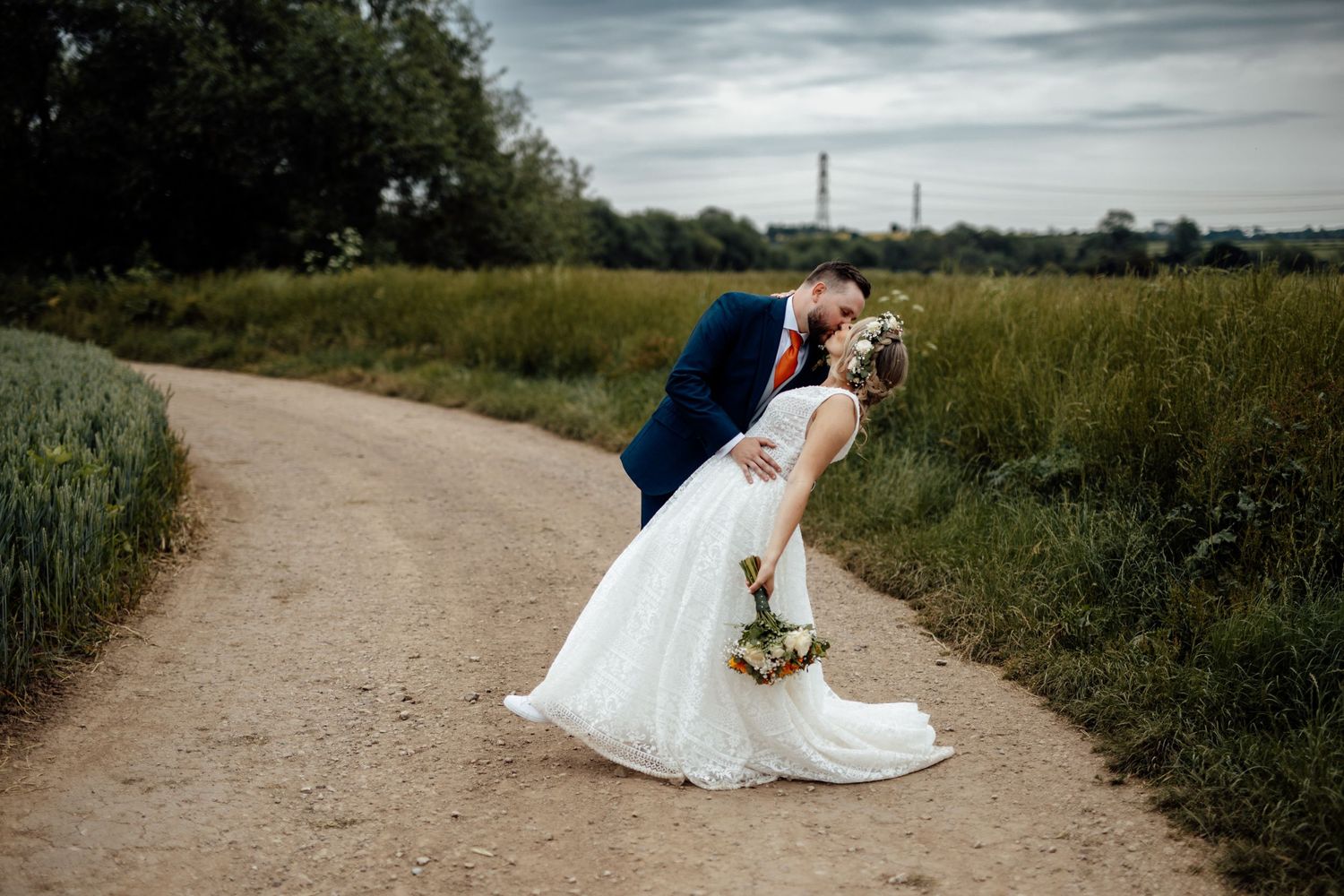 Romantic wedding portrait on a countryside path with moody sky background.