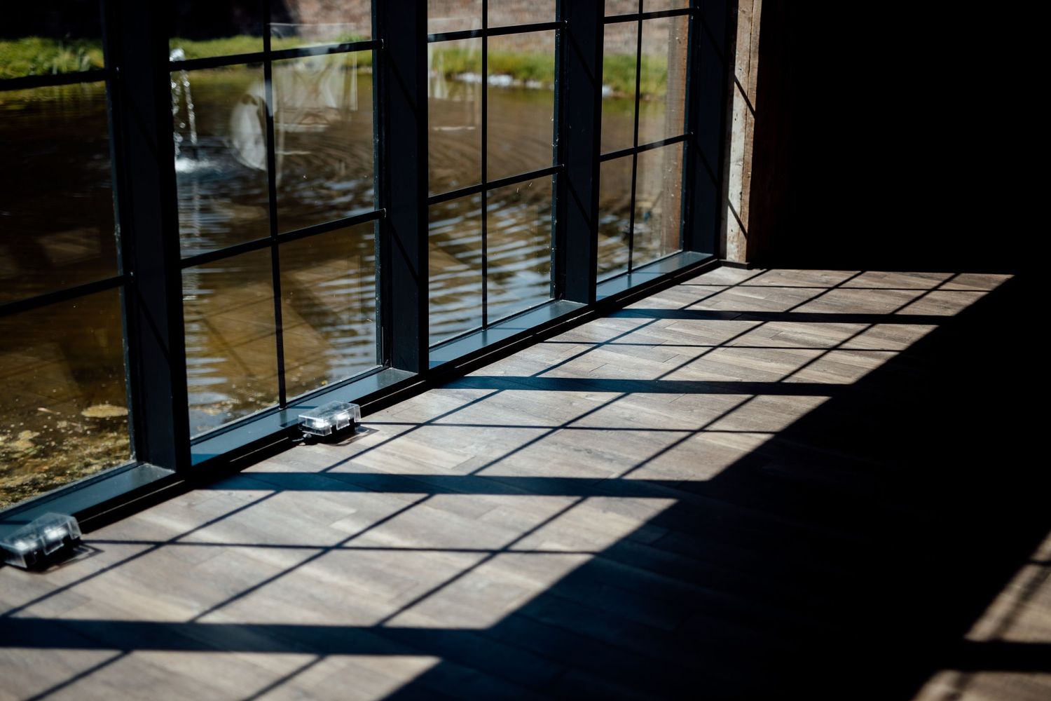 Geometric window shadows cast dramatic patterns on a modern interior floor.
