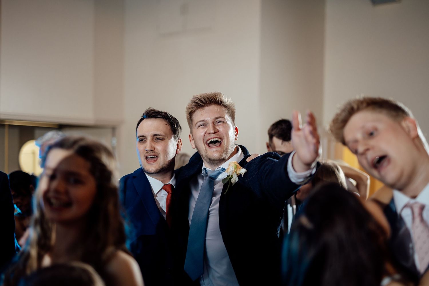Energetic wedding guests singing and celebrating during reception party.