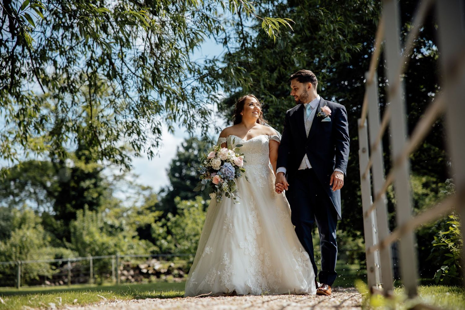 Newlyweds walking together through a scenic outdoor setting with birch trees.