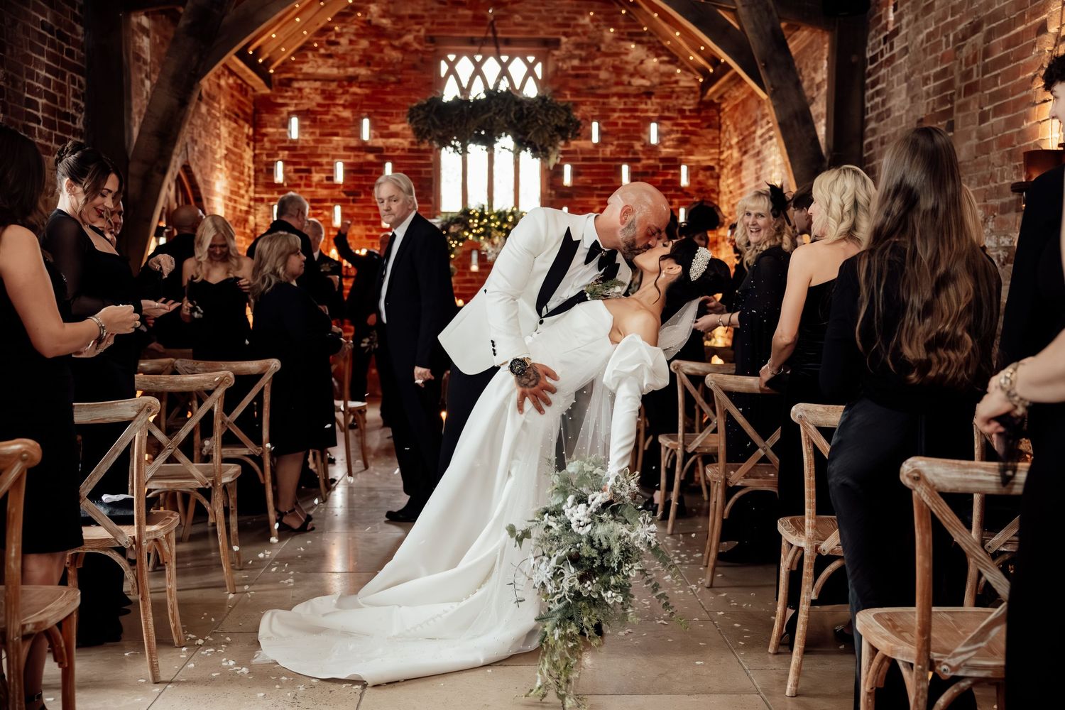 Wedding reception celebration in a rustic brick venue with elegant table settings and dancing.