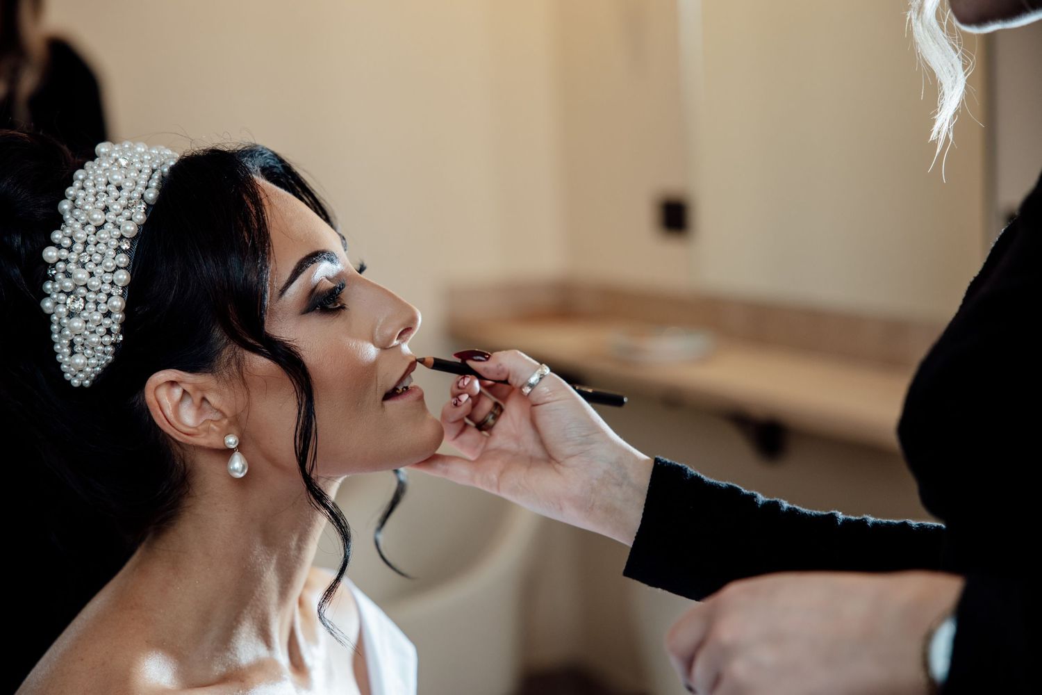 A close-up shot of someone having makeup applied with a pearl hair accessory.