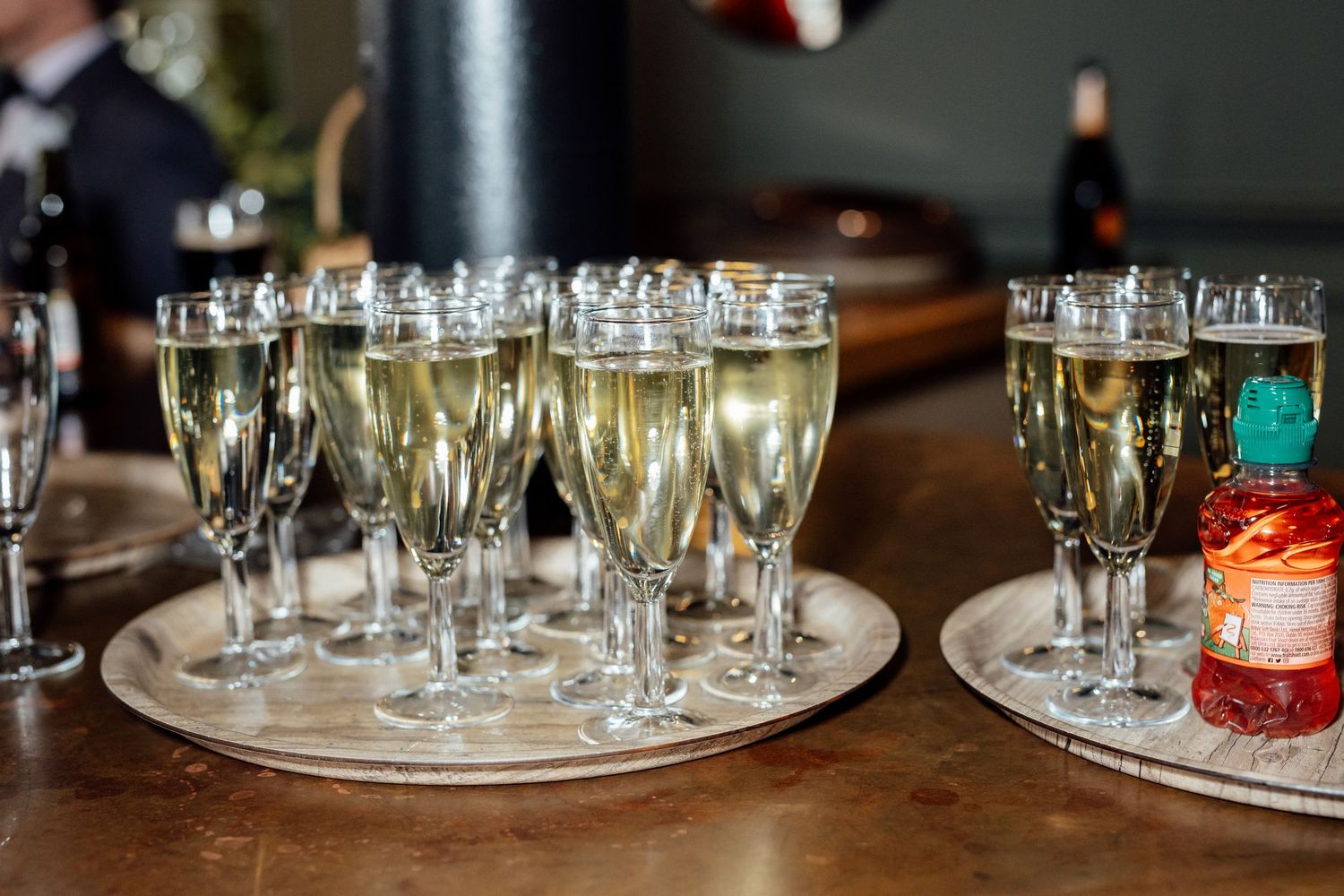 Rows of champagne flutes filled with sparkling wine arranged on silver trays at a wedding reception bar.