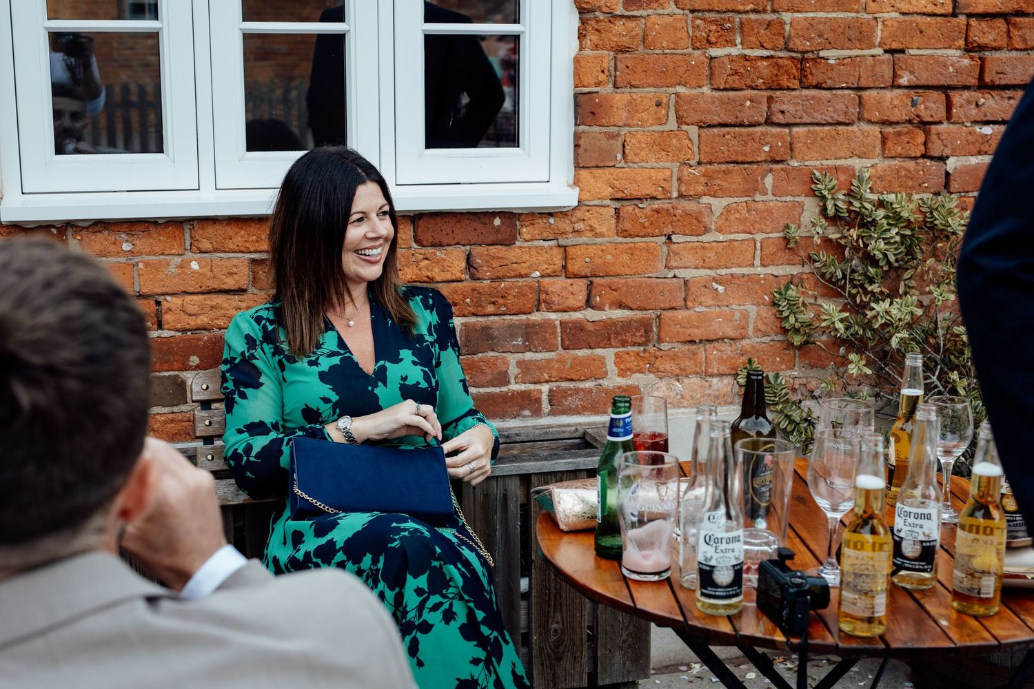Wedding reception guests enjoying drinks at outdoor brick venue.