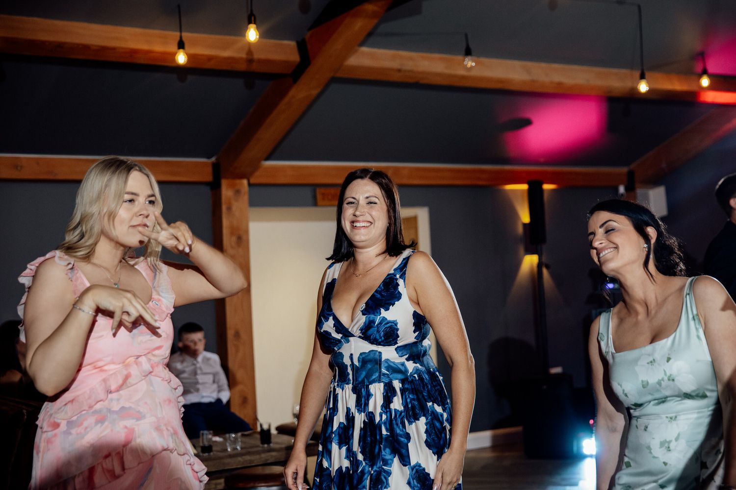 Wedding reception party guests dancing and celebrating under indoor lighting.