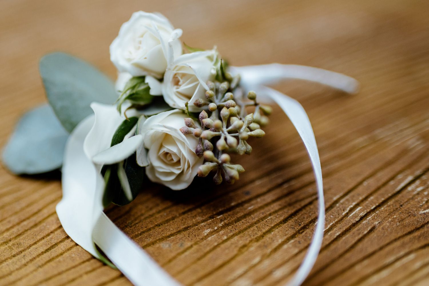Wedding accessories and floral details arranged on wooden surface.