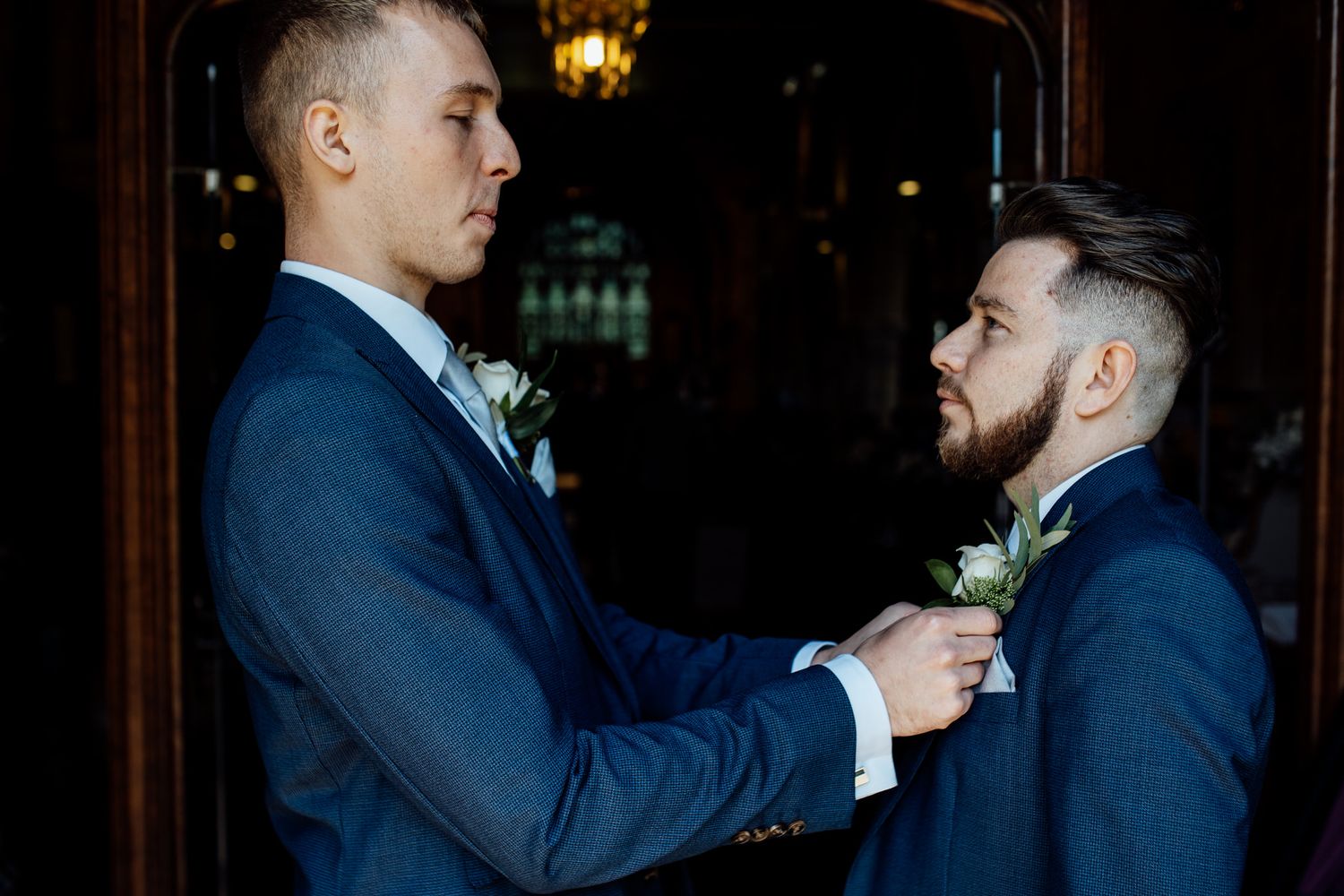 Intimate moment between couple in formal attire in a dimly lit indoor setting.