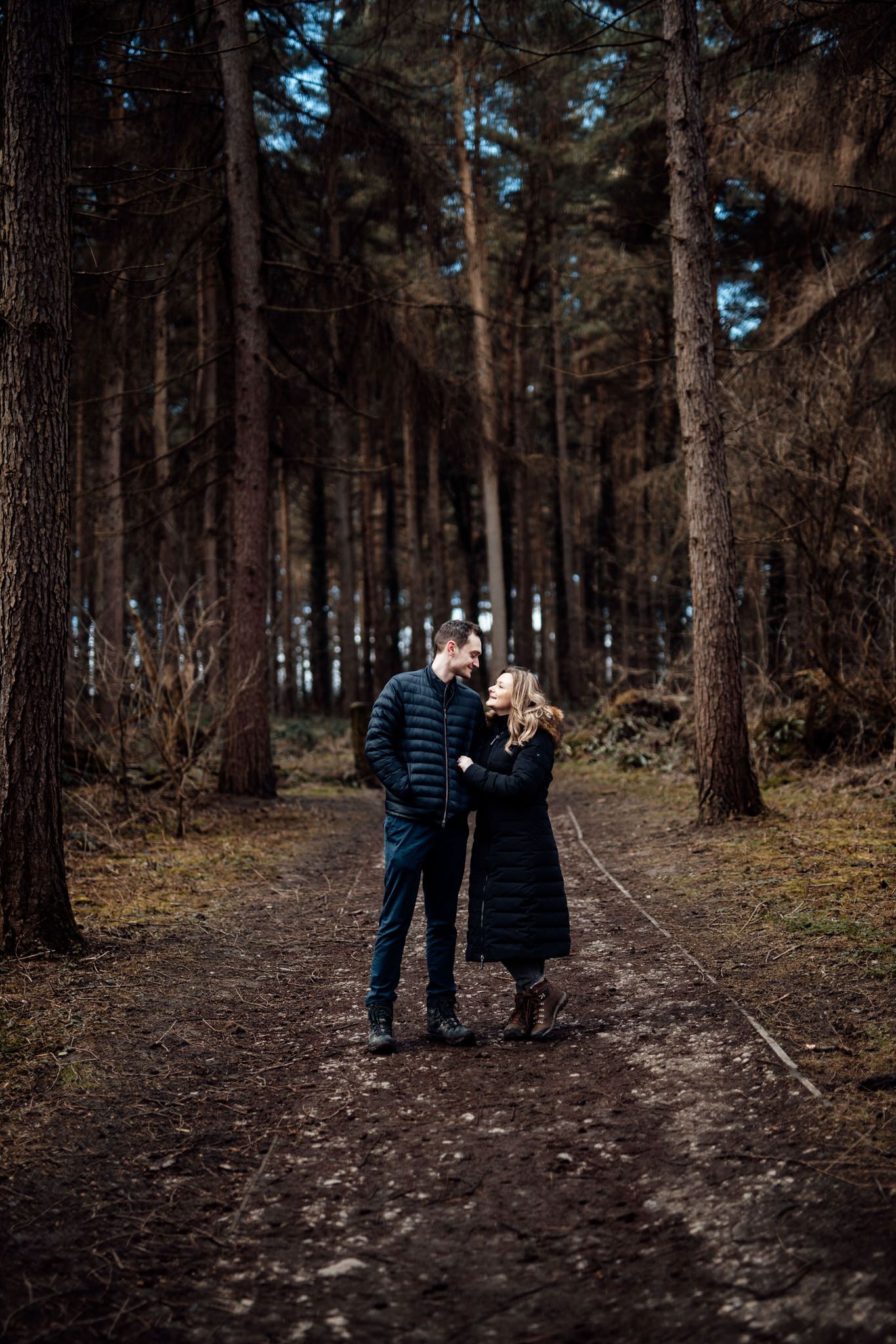 Winter engagement session in a pine forest with natural lighting.