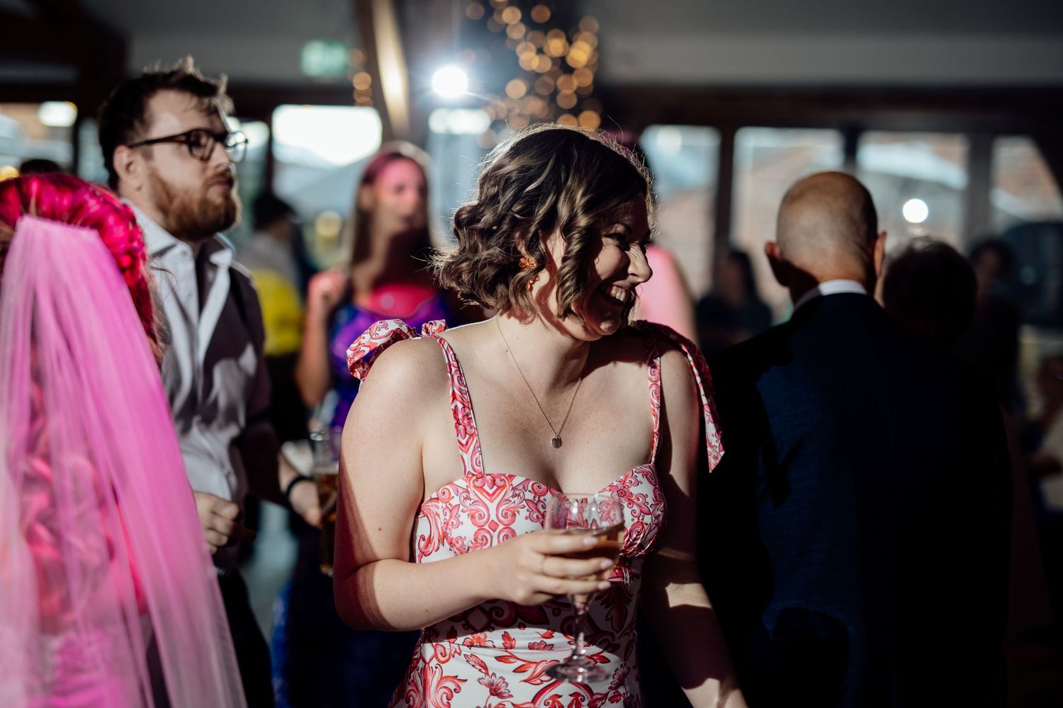 Wedding reception guests dancing and celebrating in a dimly lit venue.