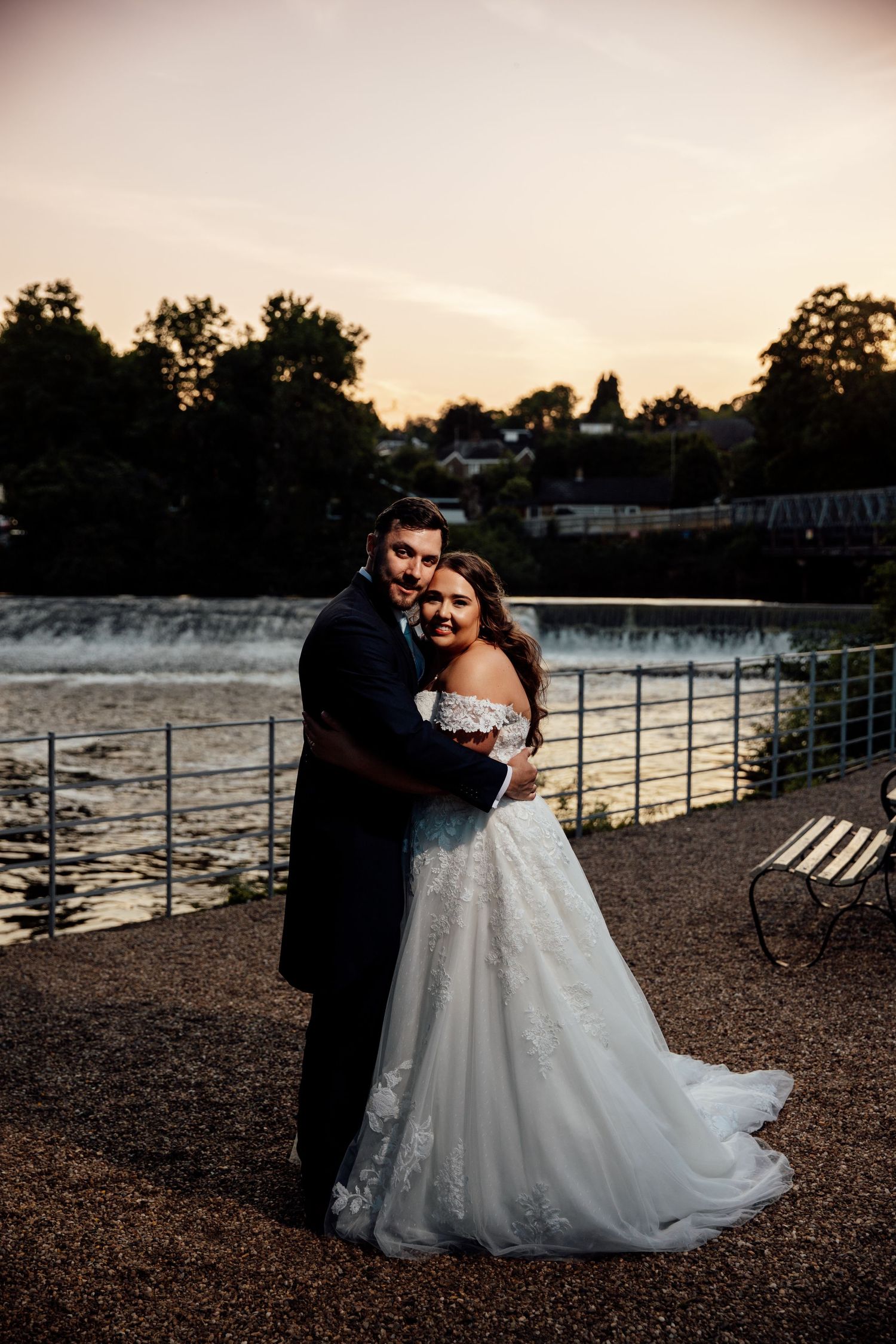 Romantic sunset portrait of newlyweds by waterfall.