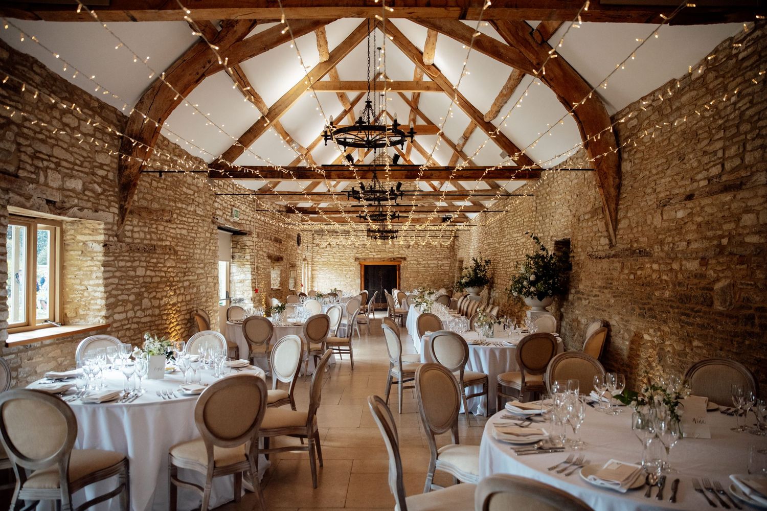 Rustic barn wedding reception venue with exposed brick walls, wooden beams, and elegant table settings.