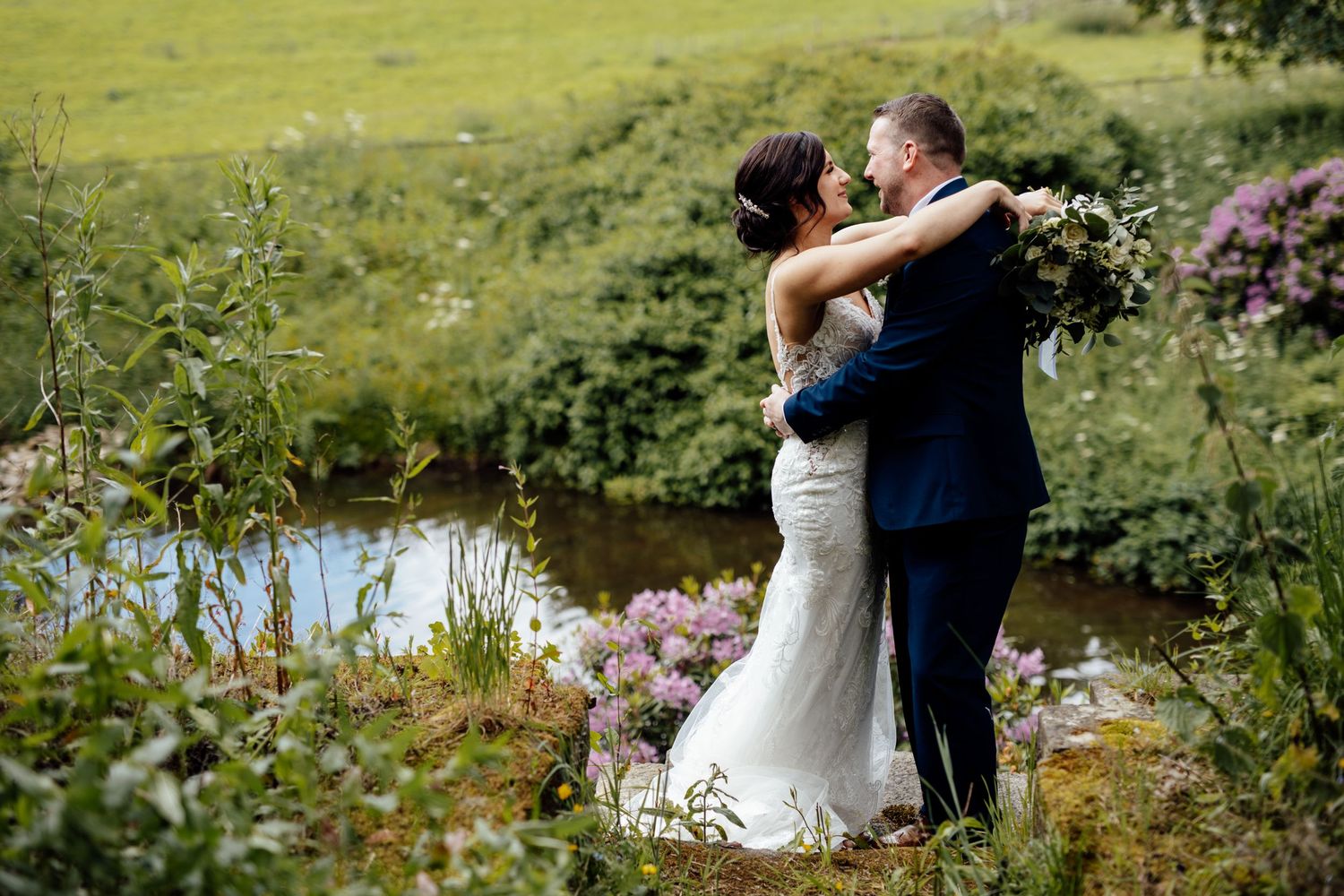 Romantic wedding portraits captured in a scenic outdoor setting with lush greenery.