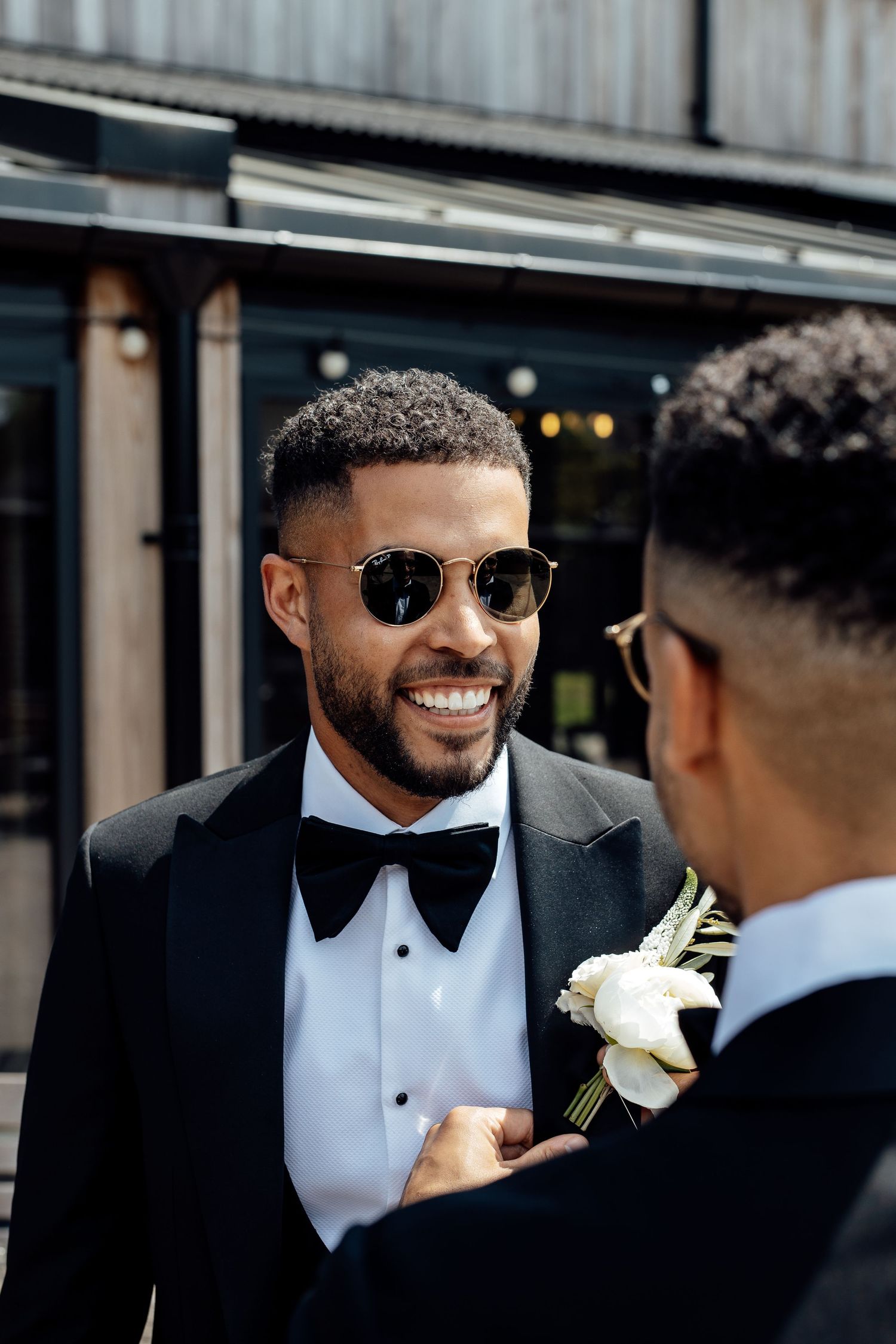 Groomsmen in classic black tuxedos share a candid moment before the ceremony.