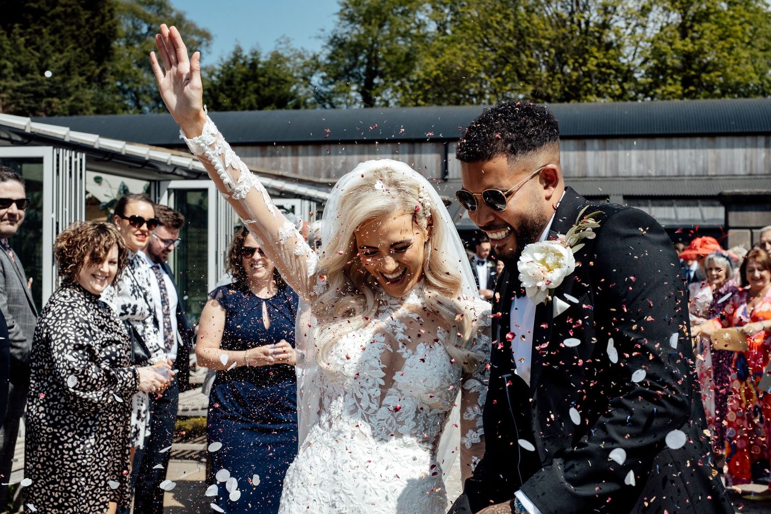 Wedding guests throw confetti during an outdoor celebration.