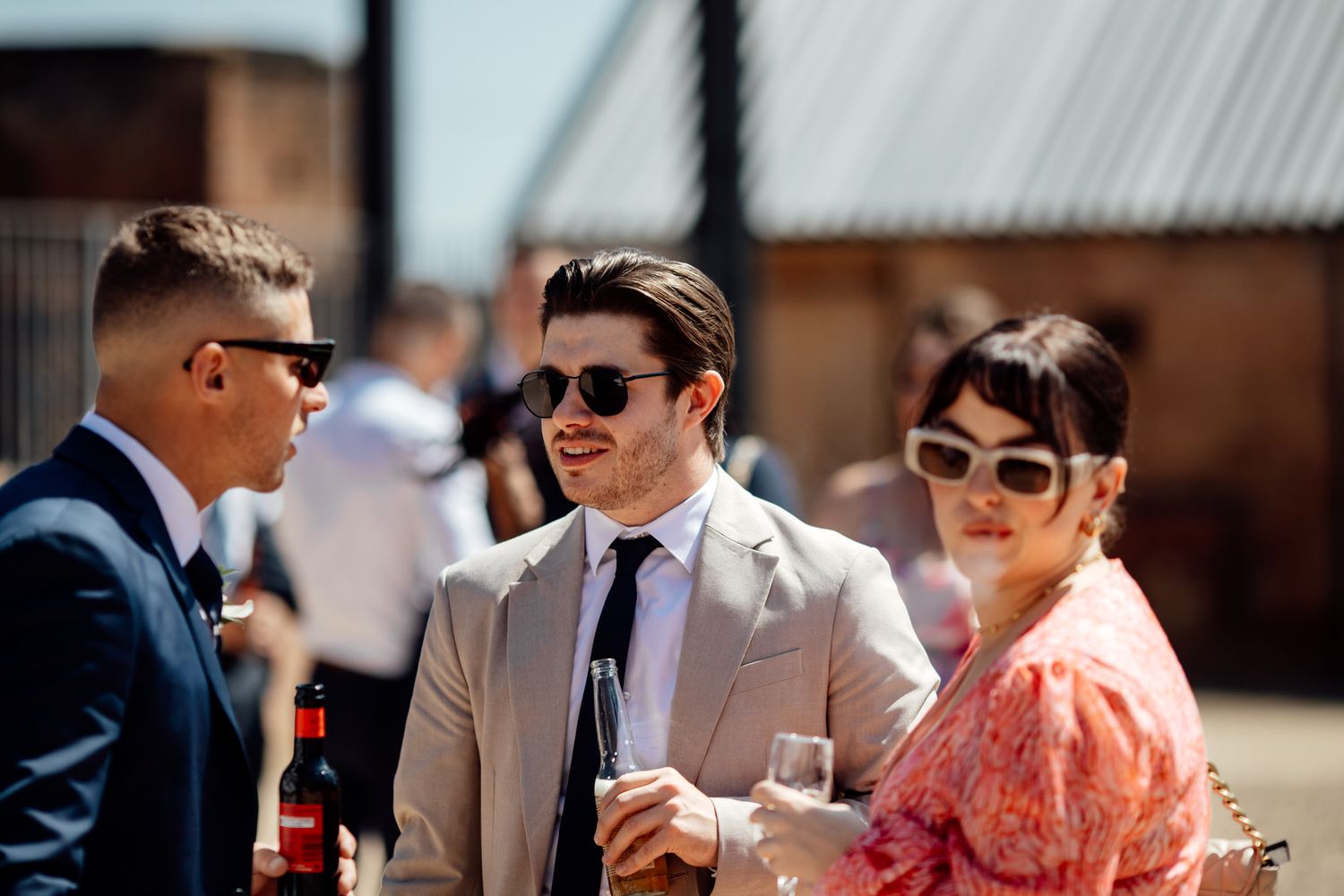 Wedding guests enjoying outdoor cocktail hour in summer attire.