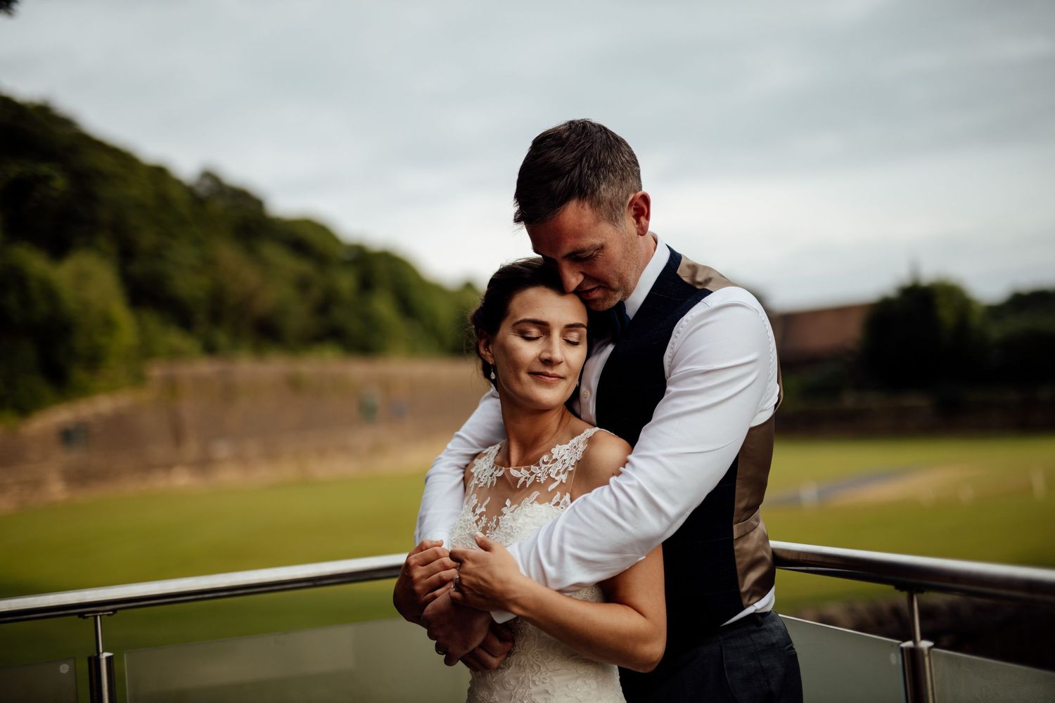 Couple embraces in romantic outdoor wedding photos against a natural landscape backdrop.