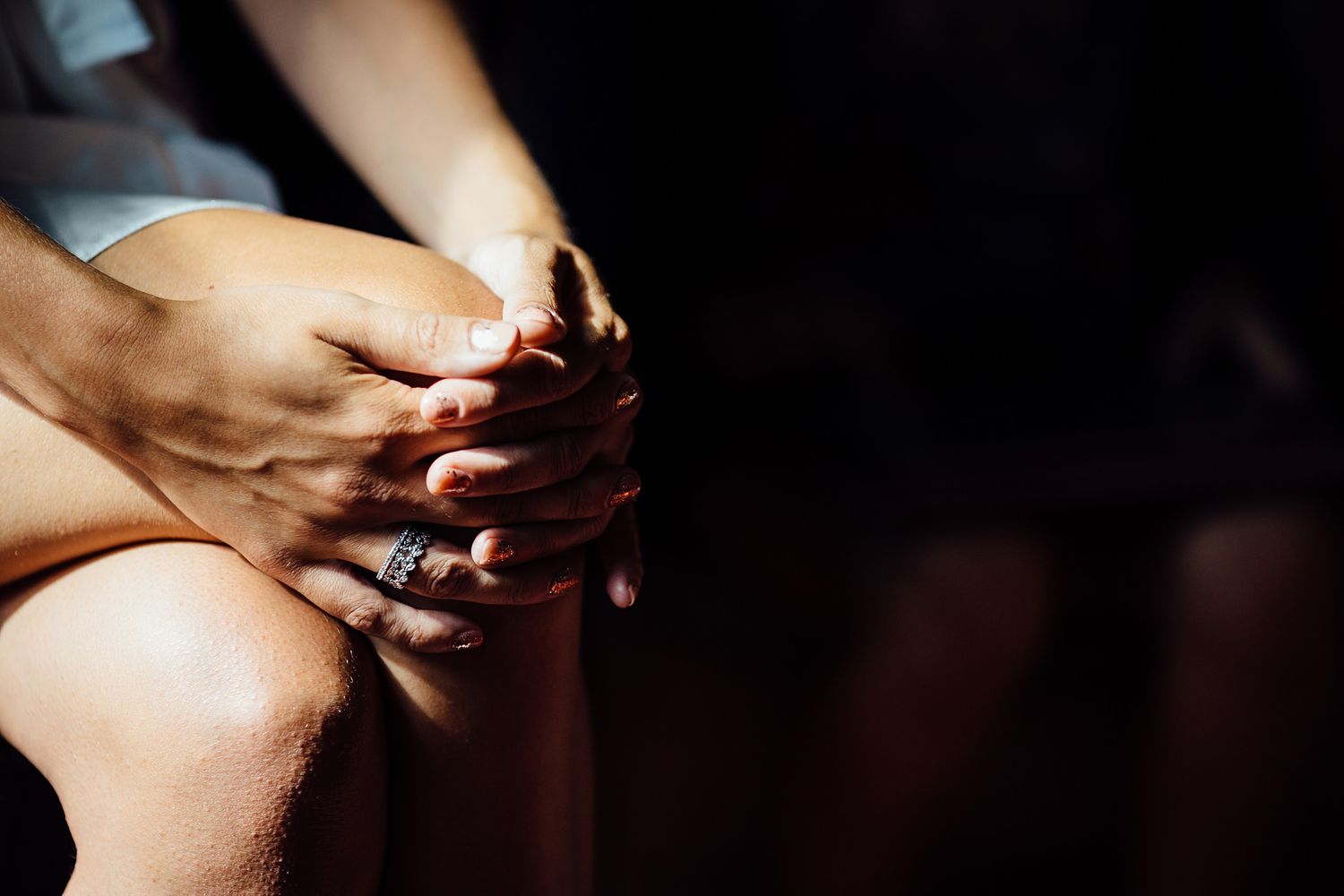 Close-up of hands in dramatic lighting during wedding preparations.