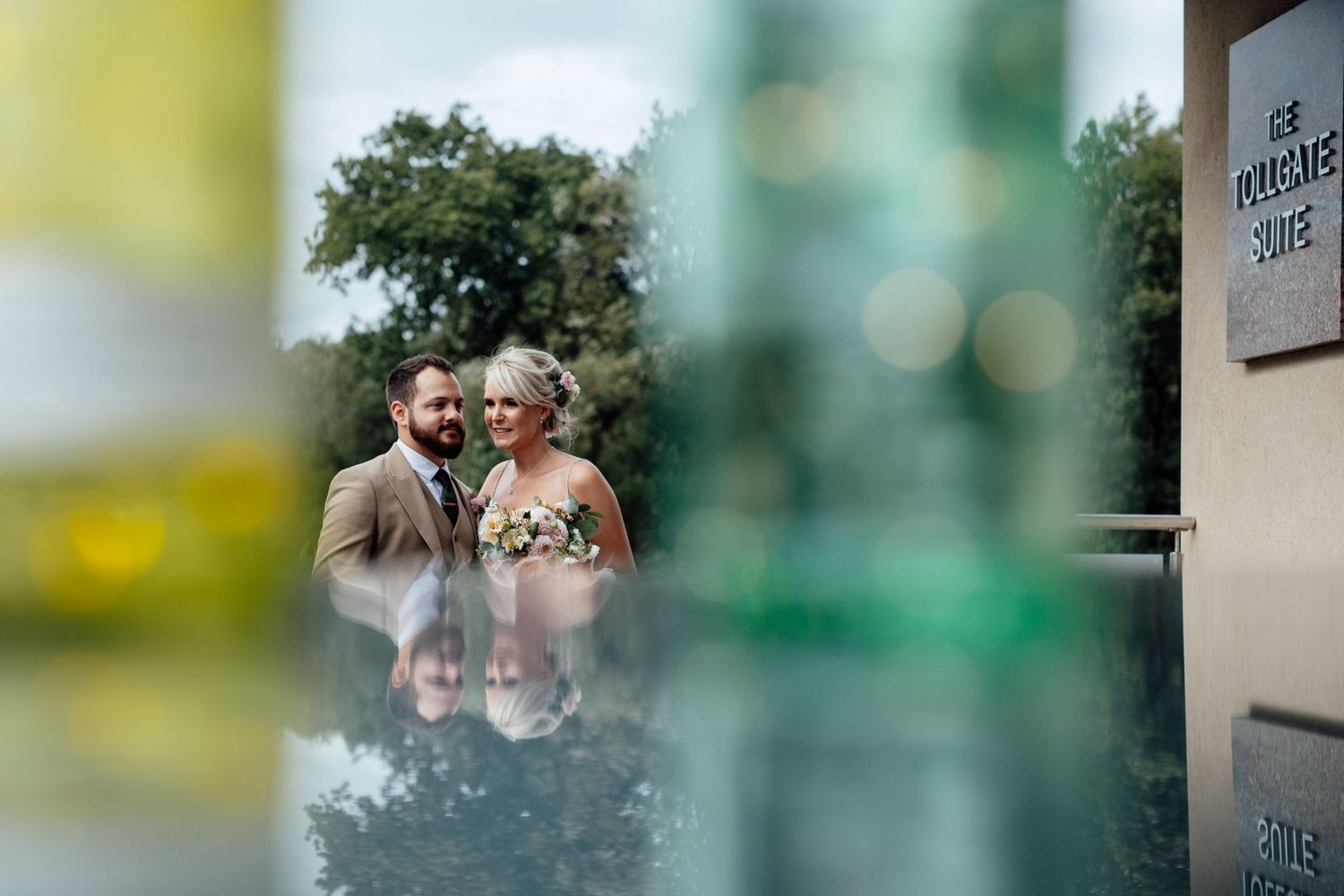 A wedding couple shares an intimate moment in front of a blurred natural outdoor background.