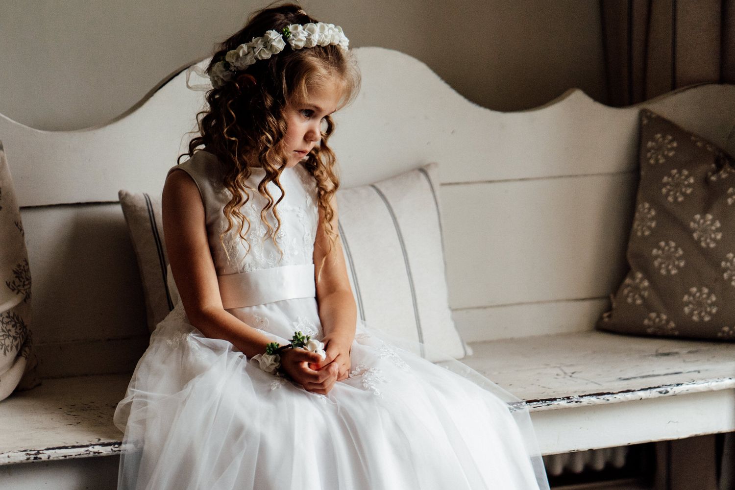 White wedding dress displayed on vintage furniture in natural light.