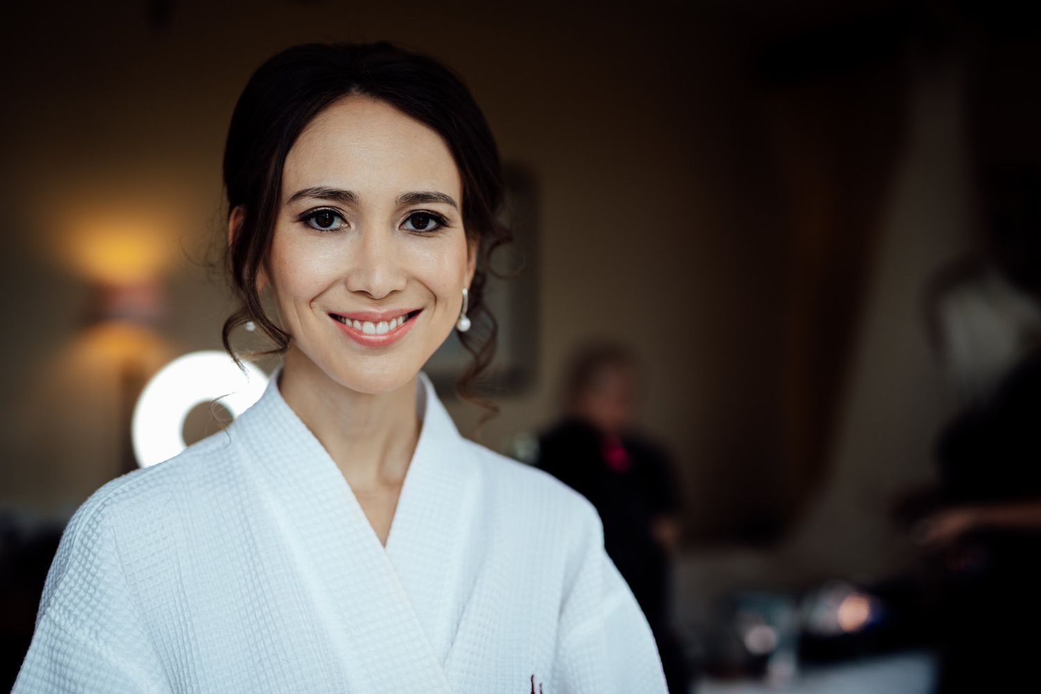 Close-up portrait of someone in a white robe with natural makeup and elegant styling.