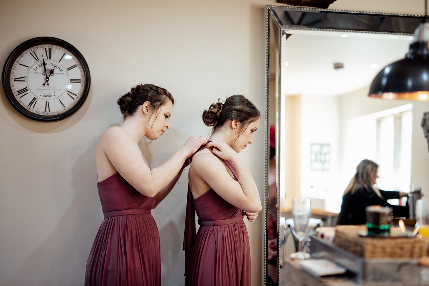 Bridesmaids in burgundy dresses share joyful moments during wedding preparations.