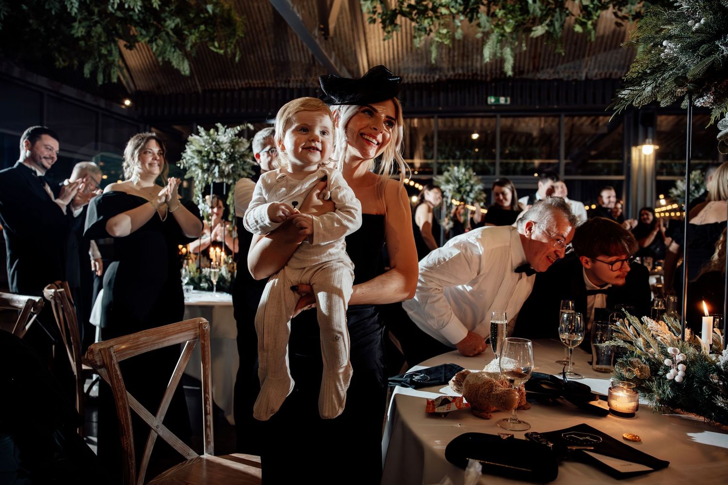 Wedding guests dancing and celebrating on a dimly lit dance floor at an evening reception.