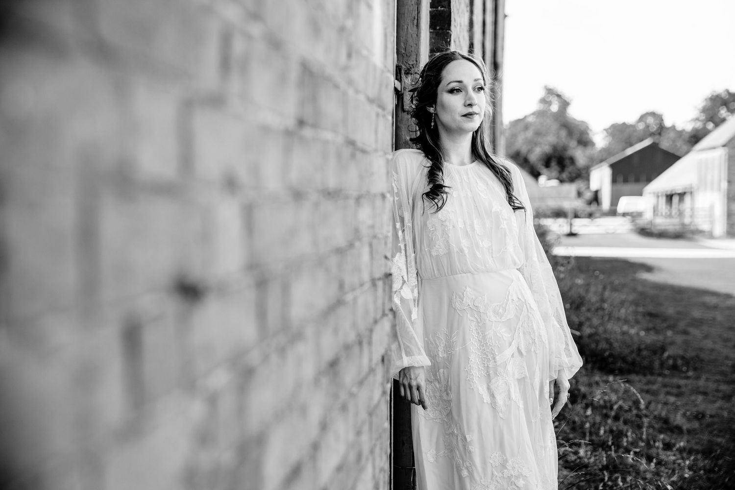 Artistic black and white portrait of a person in lace dress against stone wall.