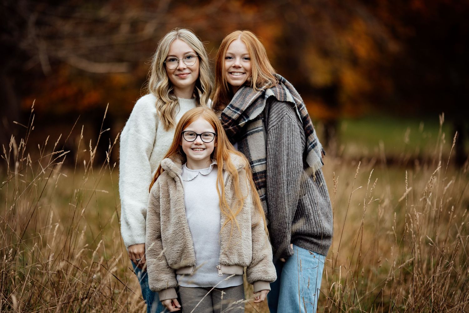 Family enjoying autumn day outdoors with fallen leaves in a park setting.