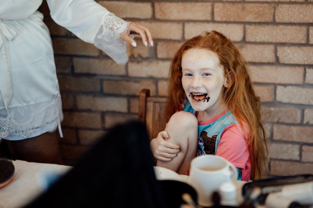 Joyful reactions during wedding preparations against exposed brick wall.