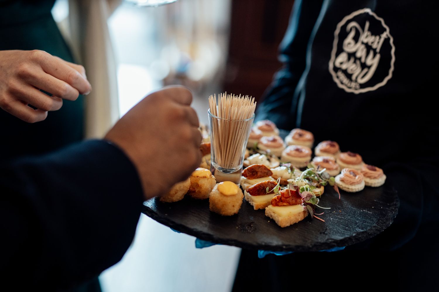 Gourmet appetizers and canapes served on dark slate plates at wedding reception.